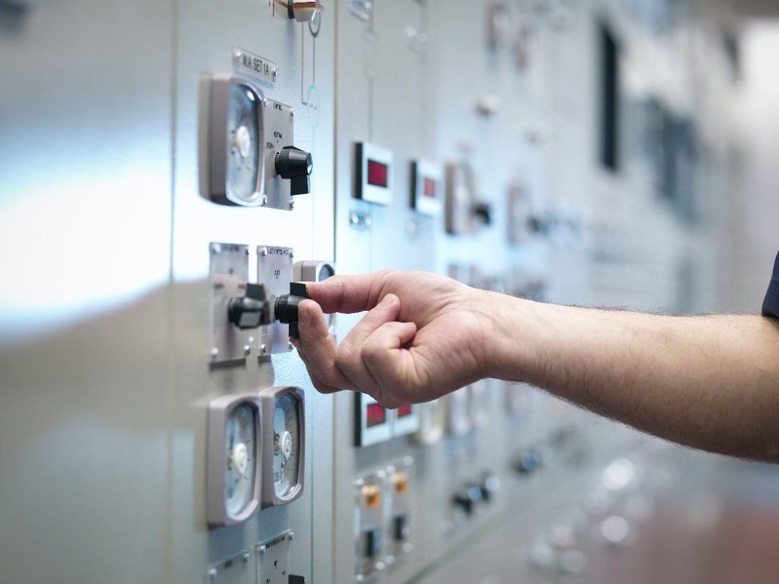 Een hand aan de knop van een bedieningsbord.