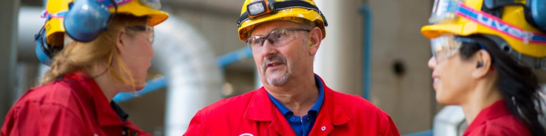 Een mannelijke en twee vrouwelijke collega's met elkar in gesprek op Shell in Pernis