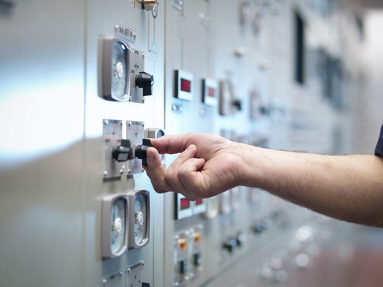 Een hand aan de knop van een bedieningsbord.