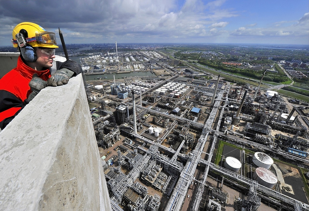 Een medewerker kijkt vanaf de schoorsteentoren van Pernis uit over Shell Energy and Chemicals Park Rotterdam