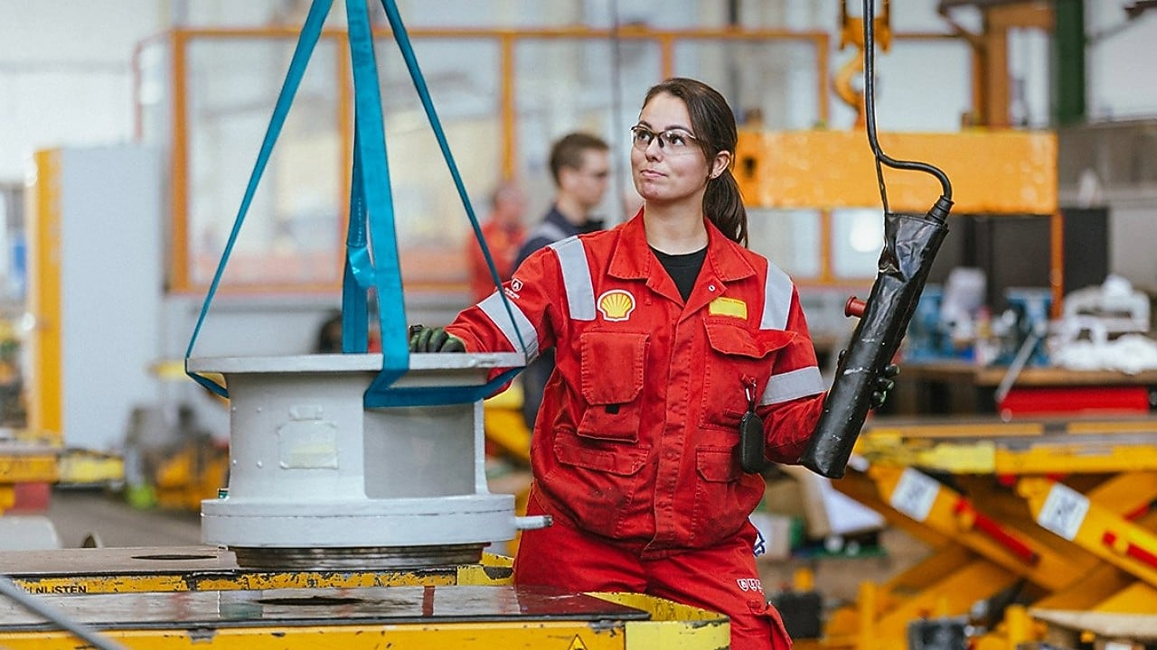 Een vrouwelijke ingenieur in rood uniform die een machine bedient