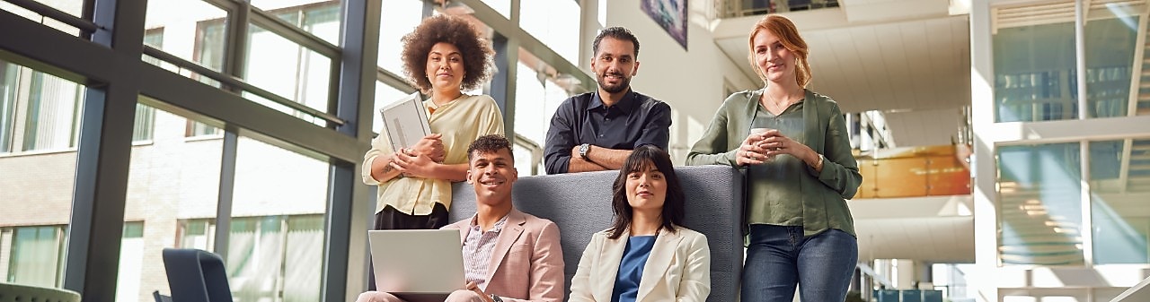 Een groep graduates (2 vrouwen, 2 mannen) zitten naast hun manager (man) en kijken naar zijn scherm