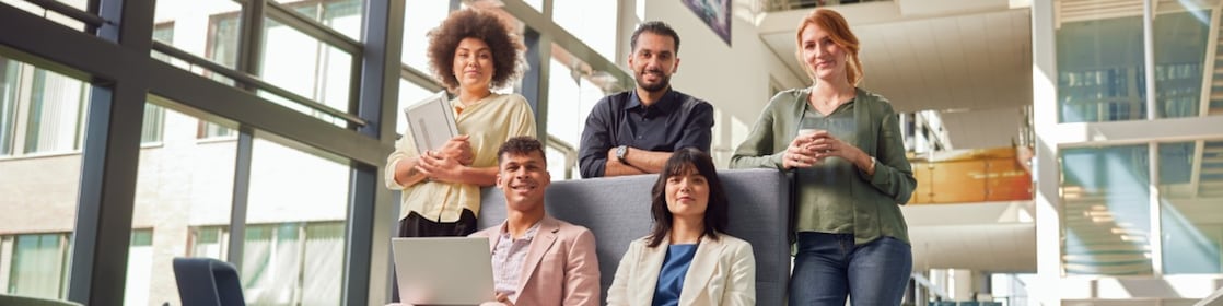 Een groep graduates (2 vrouwen, 2 mannen) zitten naast hun manager (man) en kijken naar zijn scherm
