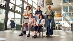Five grads are standing in a hallway smiling at the camera