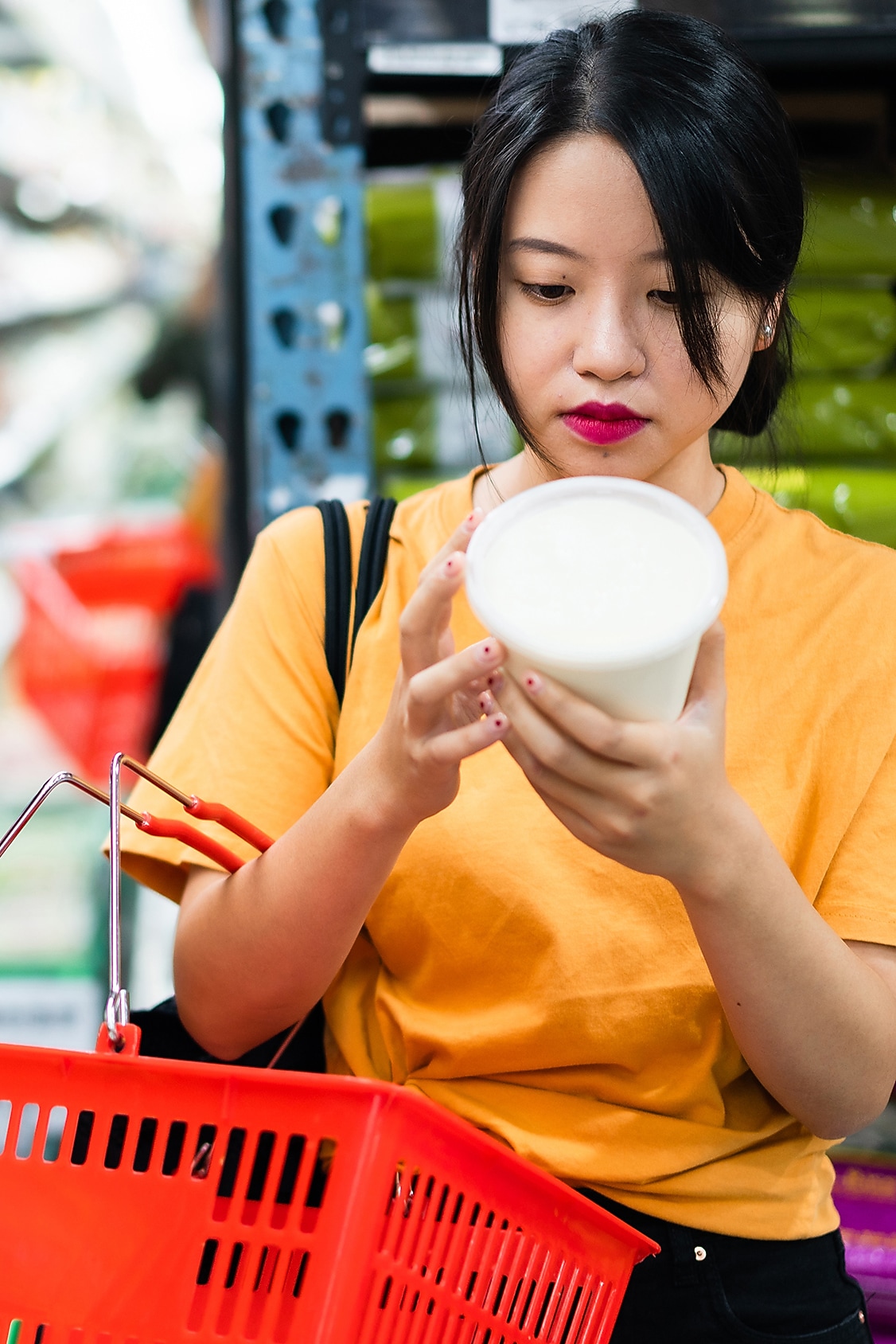 Een vrouw leest het etiket op een plastic voedingsverpakking in de supermarkt