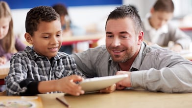 Boy showing teacher schoolwork on tablet computer