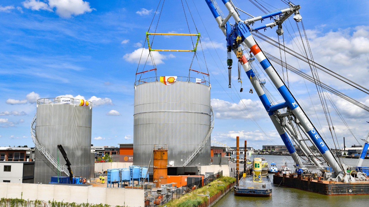 Een grote hijsbok tilt een van de opslagtanks op om …