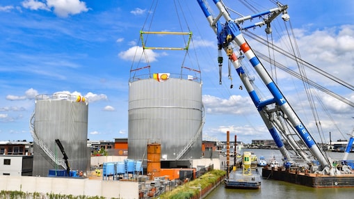 Een grote hijsbok tilt een van de opslagtanks op om …