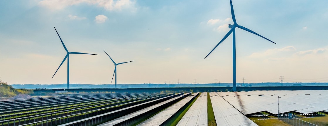 De foto toont drie windturbines en een zonnepark in het Nederlandse landschap