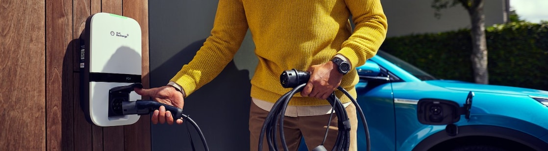 Een man laadt thuis zijn elektrische auto