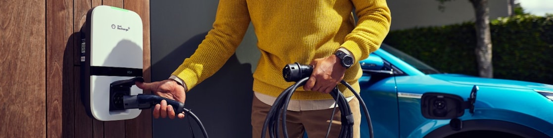 Een man laadt thuis zijn elektrische auto