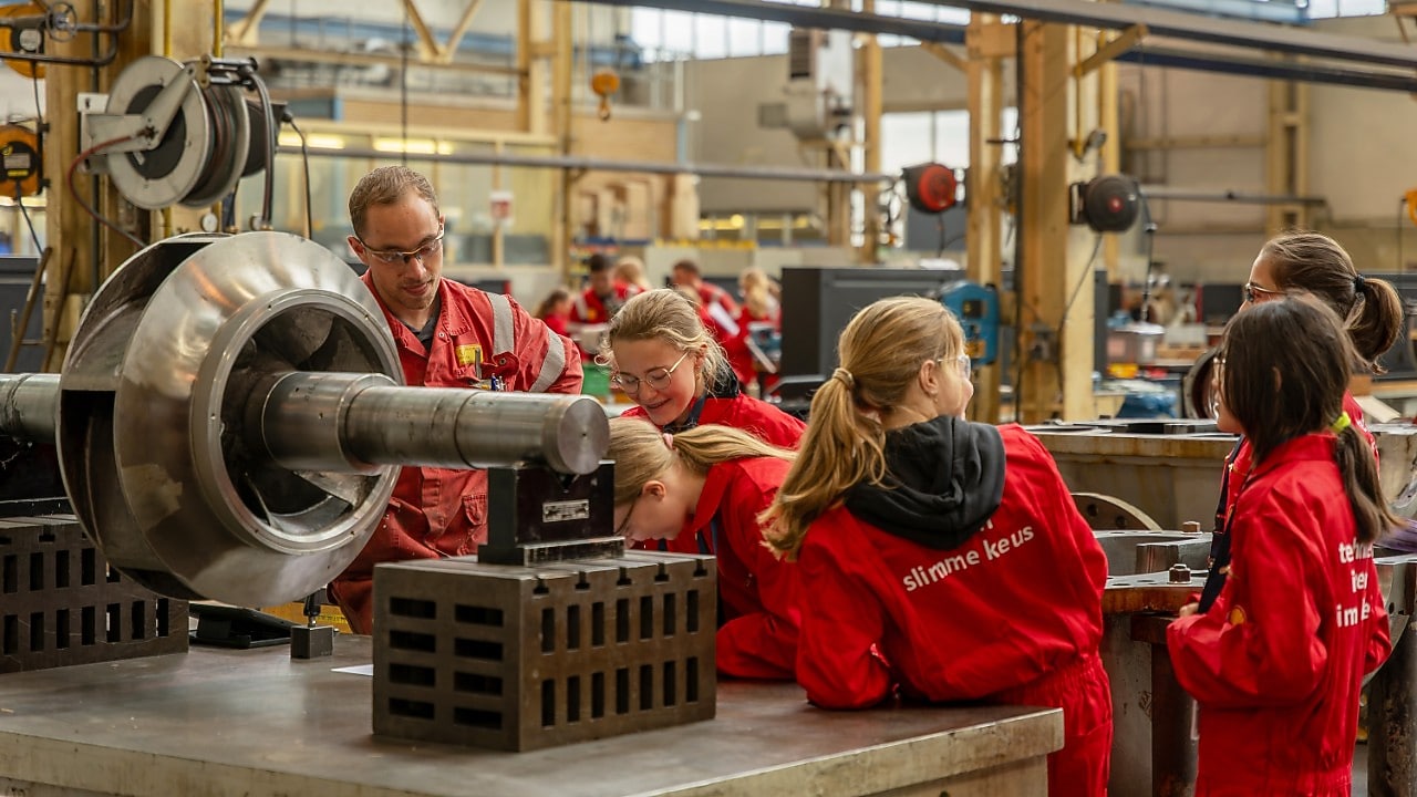 Leerlingen in rode overall nemen een kijkje in een werkplaats bij Shell in Pernis (Foto: Adriaan Schep)