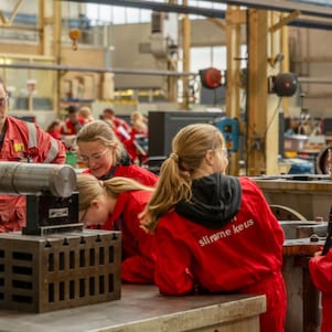Leerlingen in rode overall nemen een kijkje in een werkplaats bij Shell in Pernis (Foto: Adriaan Schep)