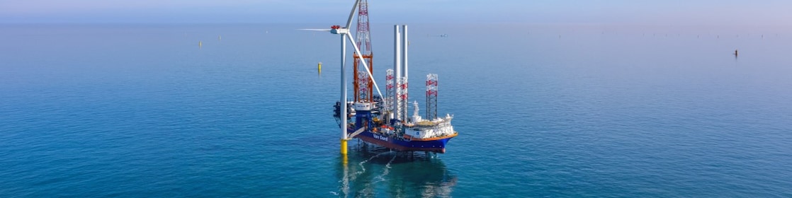 De foto toont het plaatsen van de eerste Ecowende-windturbine, 30 mei 2026 (Foto: Flying Focus). De linker- en rechterzijdes van deze foto zijn alleen in de header van dit verhaal met AI breder gemaakt om het centrale beeld goed te laten passen. De andere foto's bij dit verhaal zijn origineel zoals geschoten door Flying Focus.