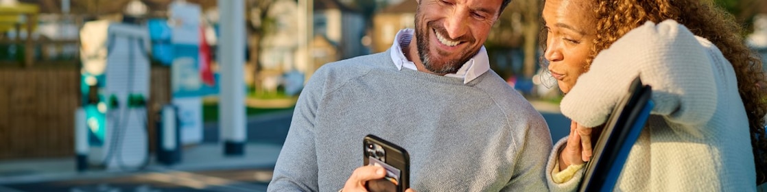 Een stel kijkt samen naar de mobiel bij een Shell Recharge-locatie (Foto: Shell Recharge)