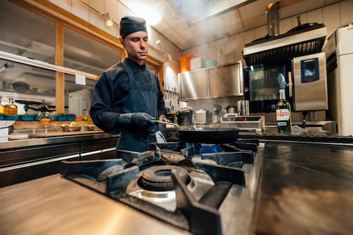 Een professionele kok in een Nederlandse keuken gebruikt de Effium-pan op het gasfornuis.