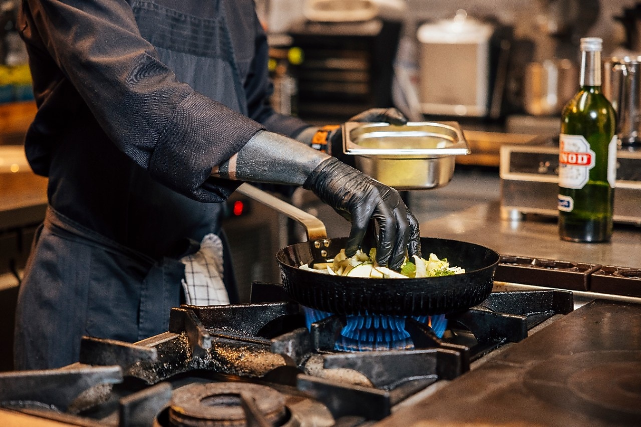 Close-up van de Effium-pan in actie. De kok husselt de groenten en andere ingrediënten in de pan die op het gasfornuis staat.