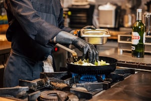 Close-up van de Effium-pan in actie. De kok husselt de groenten en andere ingrediënten in de pan die op het gasfornuis staat.