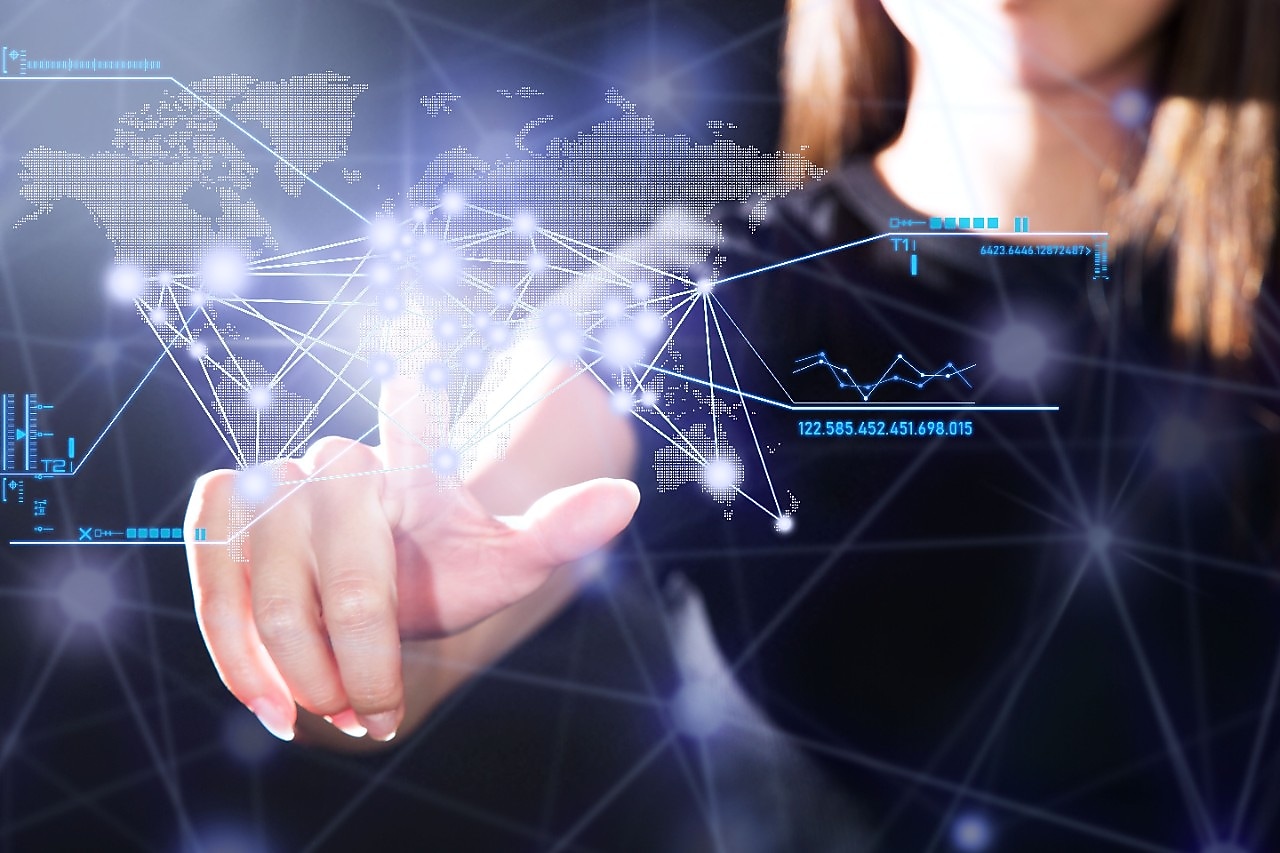 Een hand van een vrouw die op een digitaal scherm bewegingen maakt. In het scherm is een kaartje van de wereld verwerkt.