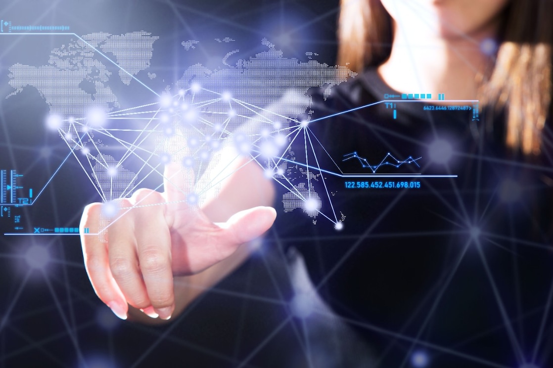 Een hand van een vrouw die op een digitaal scherm bewegingen maakt. In het scherm is een kaartje van de wereld verwerkt.