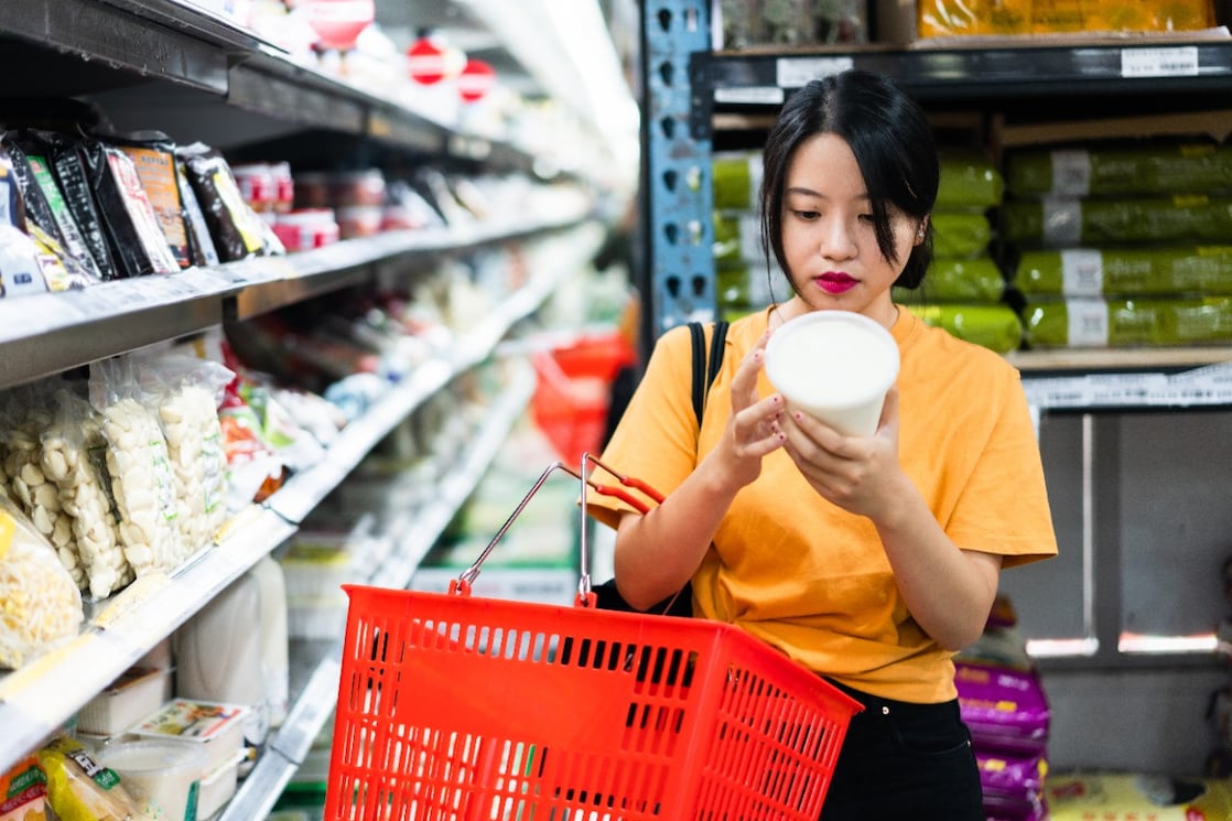 Een vrouw leest het etiket op een plastic voedingsverpakking in de supermarkt
