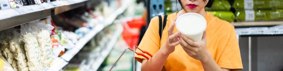 Een vrouw leest het etiket op een plastic voedingsverpakking in de supermarkt