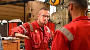 Stefan legt iets uit aan een collega. Hij gebruikt zijn rechterhand om iets aan te geven, terwijl hij oogcontact houdt met de collega die met zijn rug naar de camera staat (Beeld: Ernst Bode)