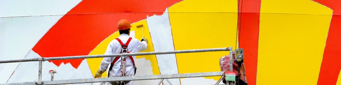 Het Shell-logo wordt op een opslagtank op Shell Energy and Chemicals Park Rotterdam (Pernis) geverfd