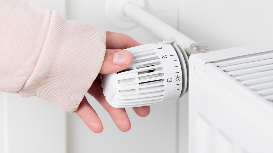 Een hand draait de radiator omhoog.