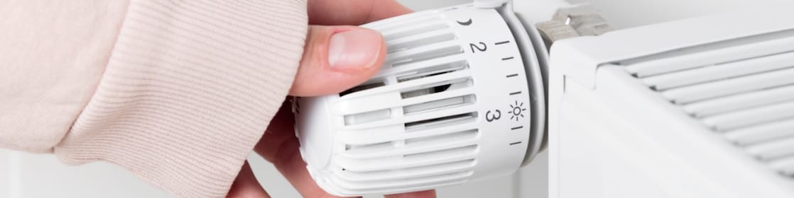 Een hand draait de radiator omhoog.
