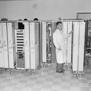 Een operator met witte jas bij kasten vol elektronica, Shell Den Haag, begin jaren 60 (Foto: Shell Heritage & Historical Archive)
