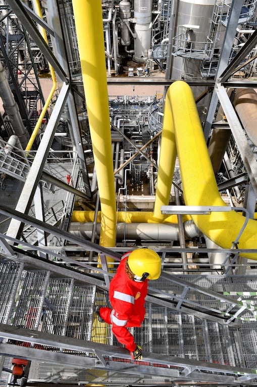 Een medewerker in beschermende kleding op de trap van een van de fabrieken van Shell in Moerdijk, tijdens een eerdere turnaround (Foto: Ernst Bode)