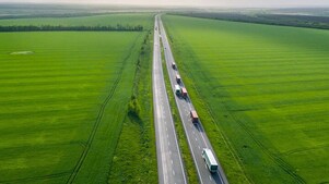 Trucks on a highway in a green field landscape
