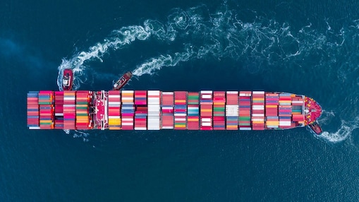 A container ship seen from above, pushed by tug boats.