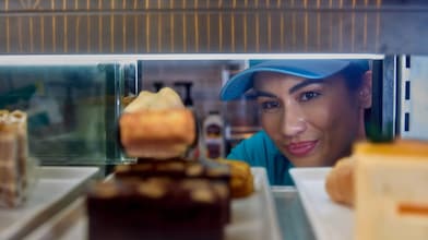 Een Shell-barista kijkt in de cake-vitrine van het Shell Café (Foto: GED Films Ltd.)