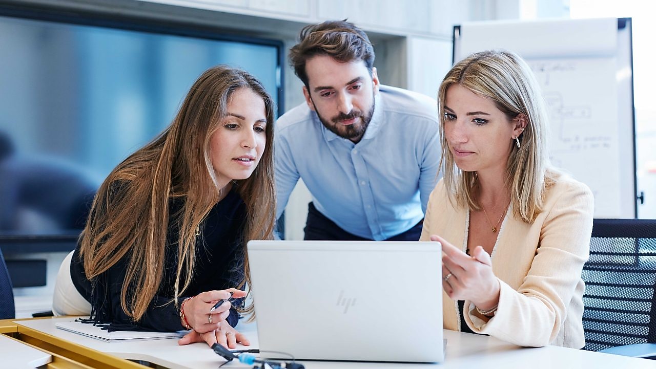 Drie collega's zitten rond een laptop