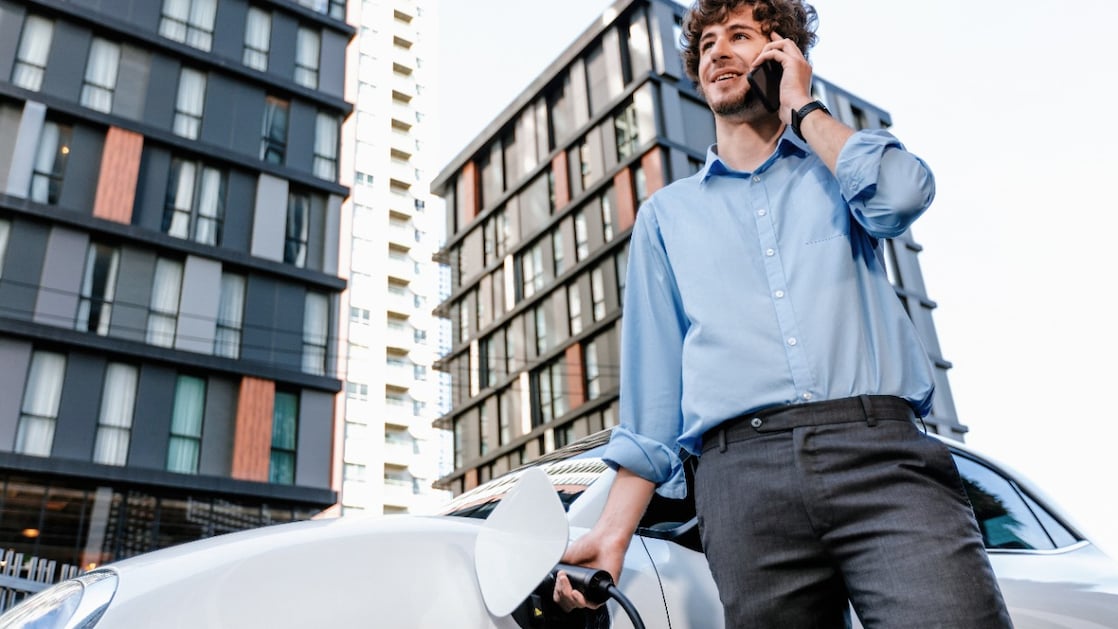 Een man laadt zijn elektrische auto in een kantooromgeving.