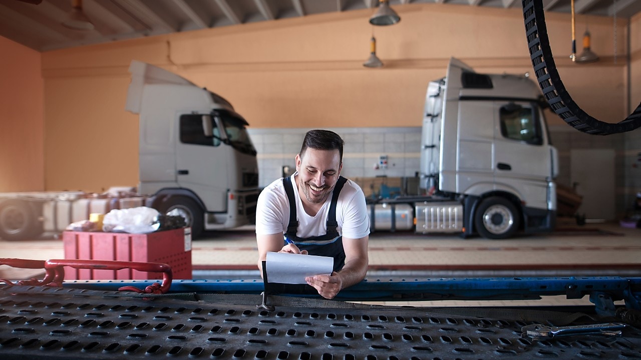 Een man met twee vrachtwagen in de achtergrond