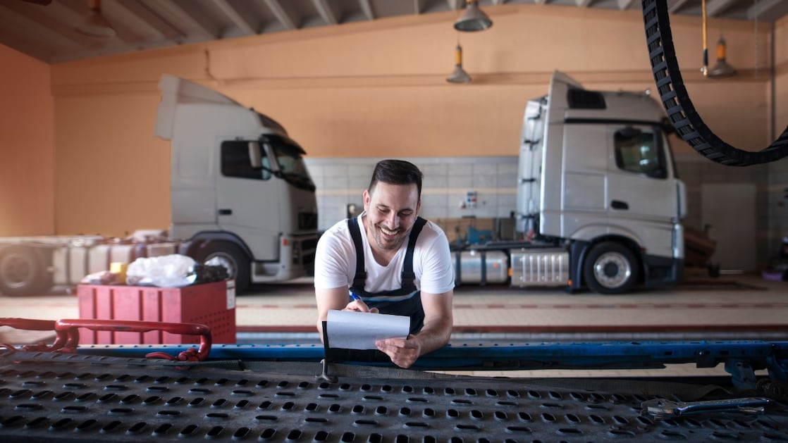 Een man met twee vrachtwagen in de achtergrond