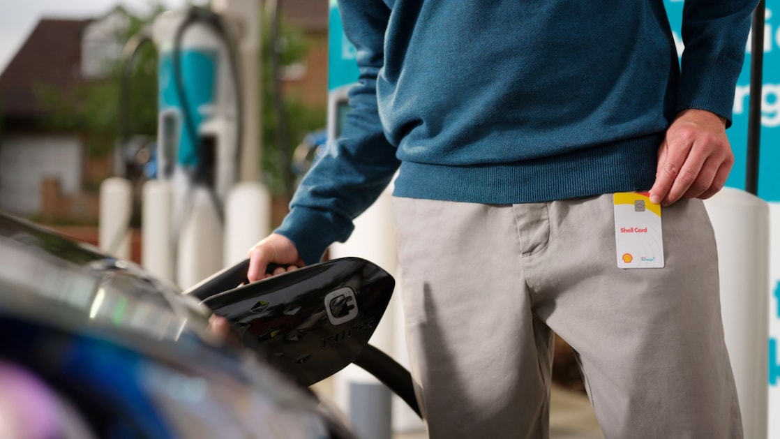 Een man tankt zijn auto en heeft de Shell Card in de hand.