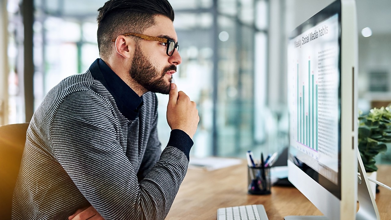 Een man kijkt op schermen met statistieken