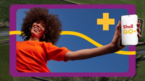 Een vrouw met oranje T-shirt houdt een mobiel vast met Shell GO+ erop
