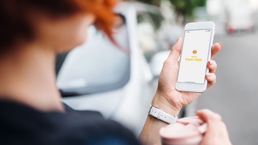Een vrouw kijkt naar haar mobiel met de Shell Fleet App.