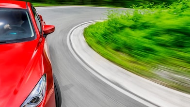 Een rode auto rijdt over een weg