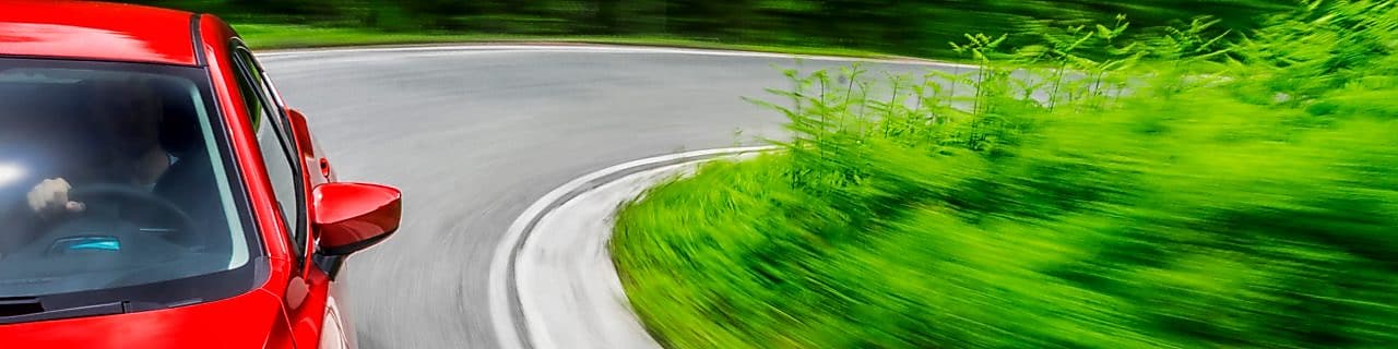 Een rode auto rijdt over een weg