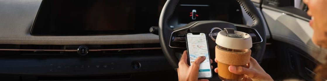 Driver is enjoying a coffee and using the Recharge App in their parked car at a Charge Point.